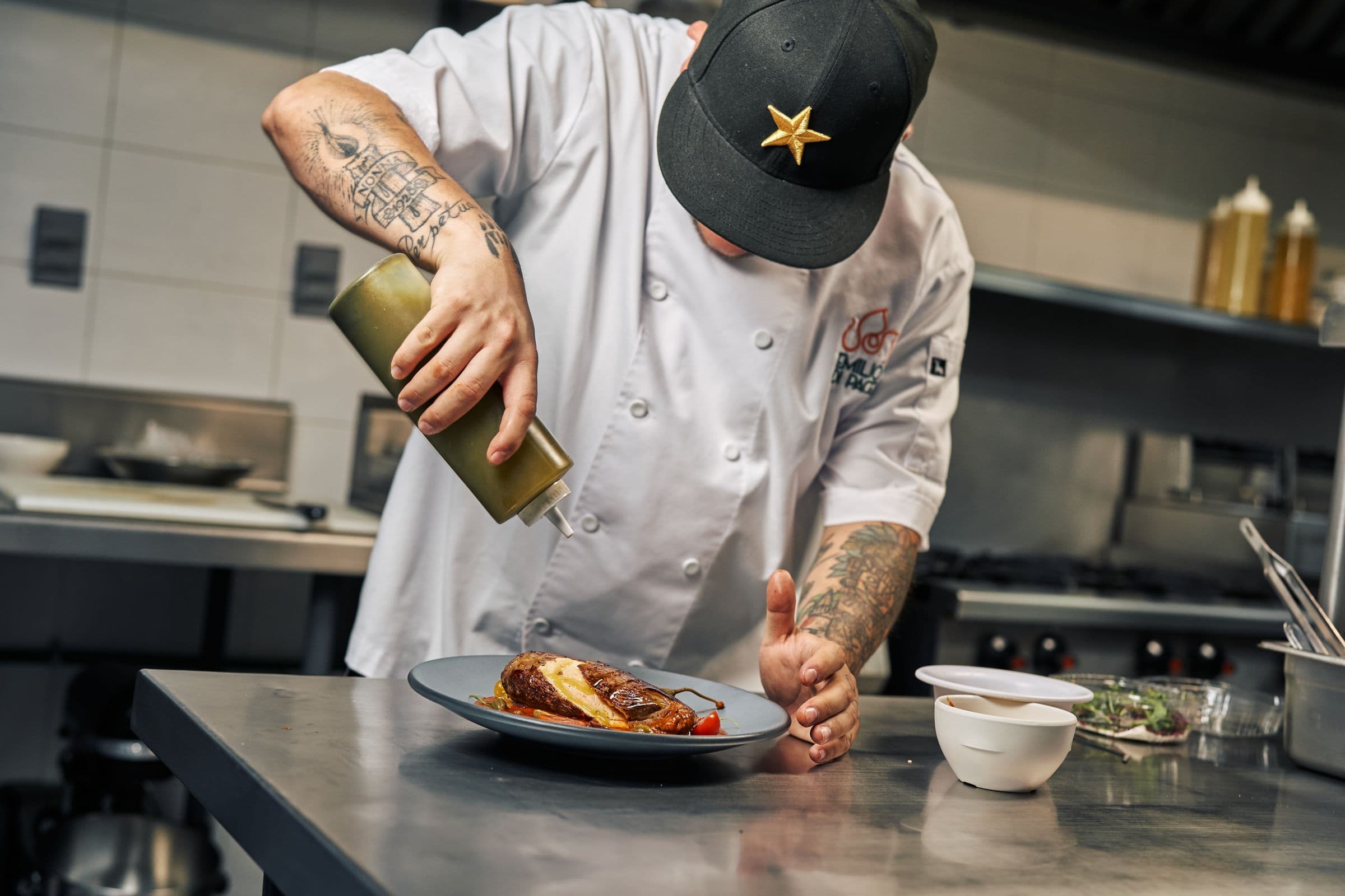 A chef finishing a plated dish on the kitchen pass during service